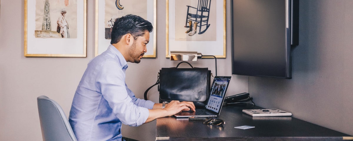 Man working at hotel room desk - Maximize Vacations