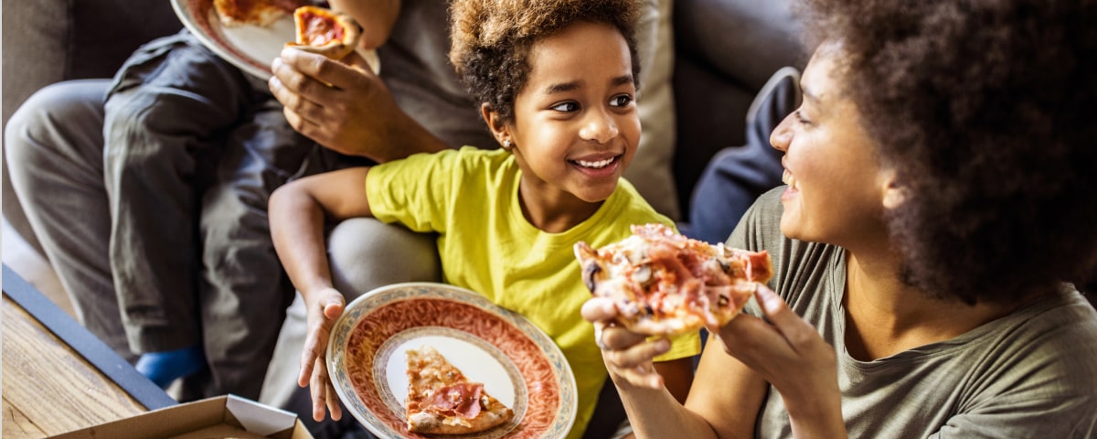 A family enjoying some pizza. - Learn more about the Eat and Earn program